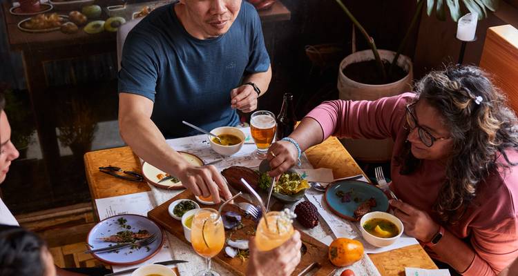 Group dining around a table with a variety of colorful dishes.