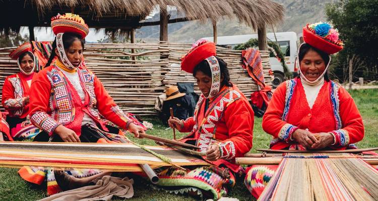 Femmes en vêtements traditionnels tissant en plein air dans un cadre de marché.