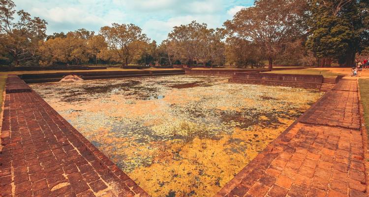 A scenic view of an ancient water reservoir surrounded by trees and paths.