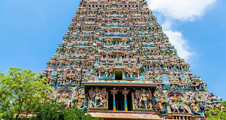Vibrant, intricately carved gopuram tower of Meenakshi Temple reaching into blue sky.