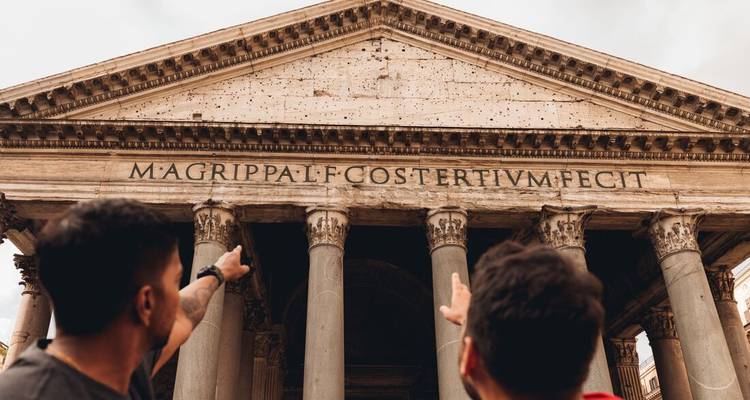 Les voyageurs pointent du doigt vers la façade grandiose du Panthéon avec son inscription latine et ses colonnes.