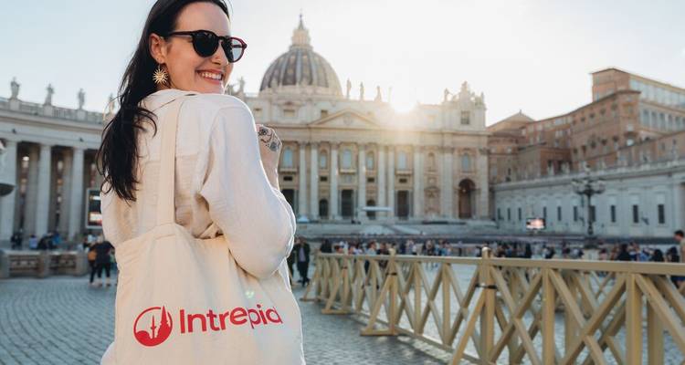 Une femme avec un sac cabas souriante devant un bâtiment historique.