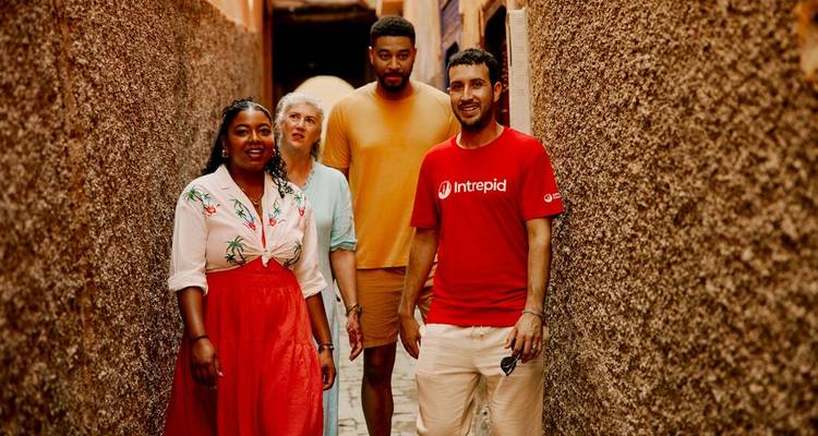 Pequeño grupo caminando por un estrecho callejón ocre entre paredes con texturas