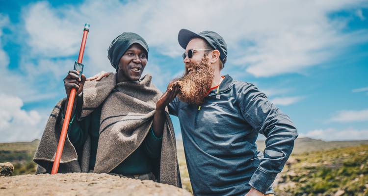 Deux hommes debout sur une colline avec un vaste paysage en arrière-plan.