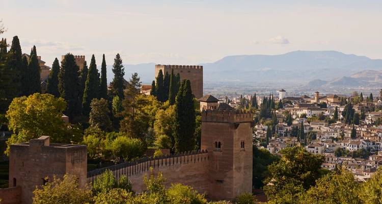 Vue panoramique de la forteresse de l'Alhambra et de la ville de Grenade avec des montagnes lointaines sous une douce lumière d'après-midi.