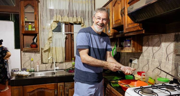 Homme souriant en préparant un repas dans une cuisine.