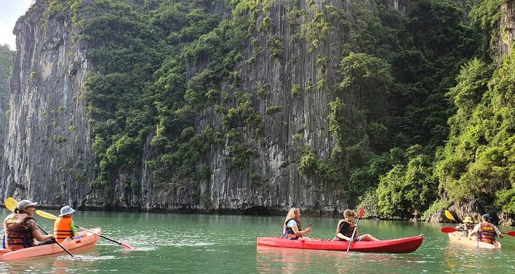 Plusieurs kayaks sur une eau turquoise claire avec d'imposantes falaises vertes.