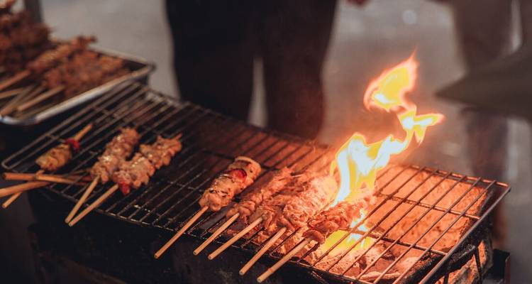 Brochettes grésillant sur un feu ouvert sur un gril de restauration de rue