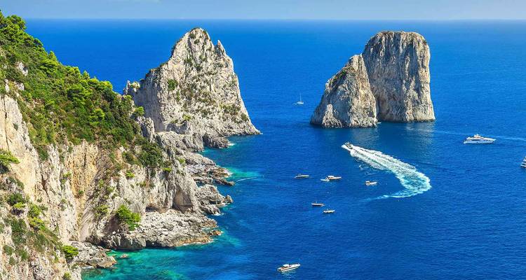 Aerial view of Capri’s rugged cliffs, emerald coves and the Faraglioni stacks framed by turquoise sea.