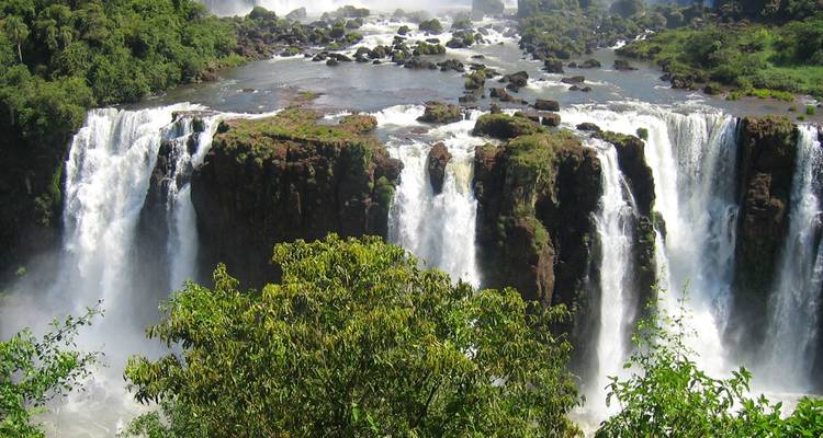 Powerful cascades of Iguazu Falls plunge into a misty gorge surrounded by lush jungle.