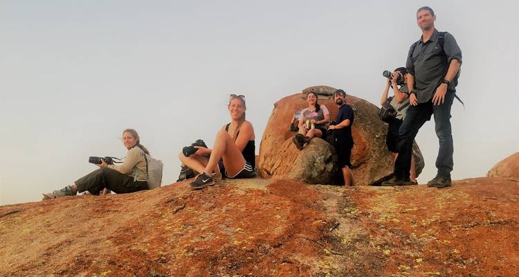 Groupe de personnes sur une colline rocheuse, prenant des photos.