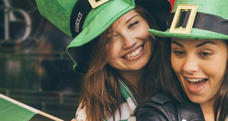 Two women celebrating with Irish hats and a flag.