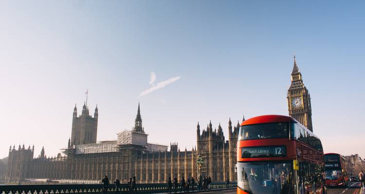 Iconic red double-decker buses cross Westminster Bridge beneath the spires of the Houses of Parliament and Big Ben.