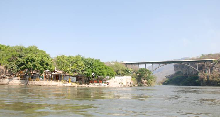 Scène de rivière avec un pont en arrière-plan.