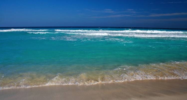 Hermosa playa con agua turquesa y olas.