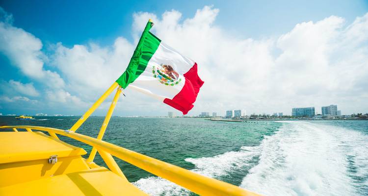 Paseo en barco con una bandera mexicana y el horizonte de la ciudad.