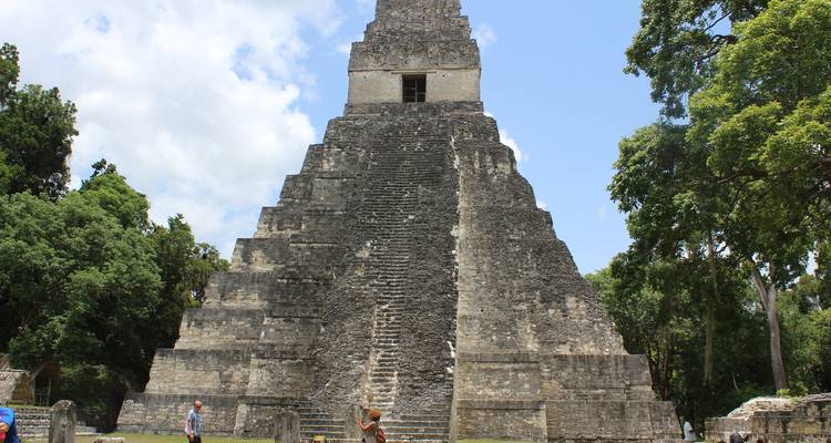Une pyramide maya historique entourée de touristes et d'une végétation luxuriante.
