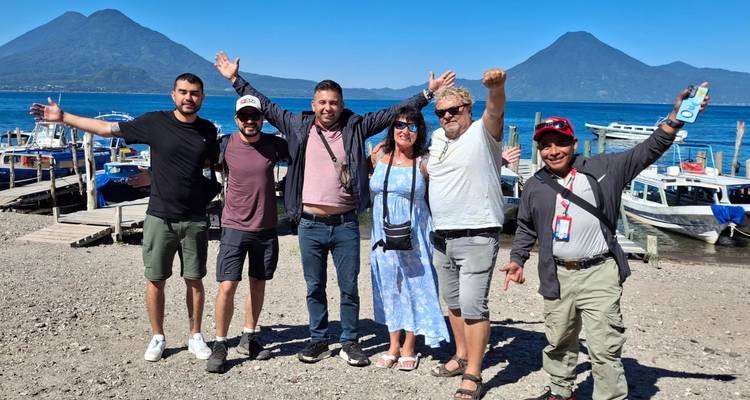 Grupo de turistas posando frente a un lago con montañas