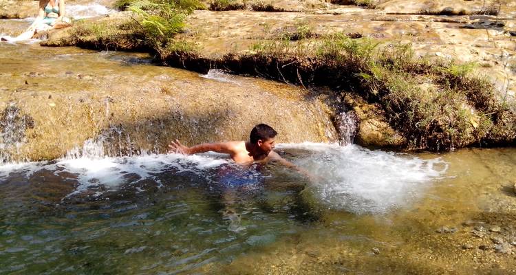 Child playing in a small waterfall with rocks and water.