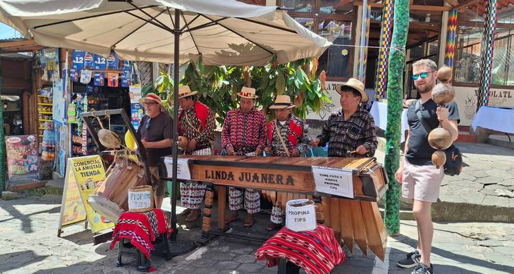 Músicos callejeros tocando marimba con transeúntes observando.