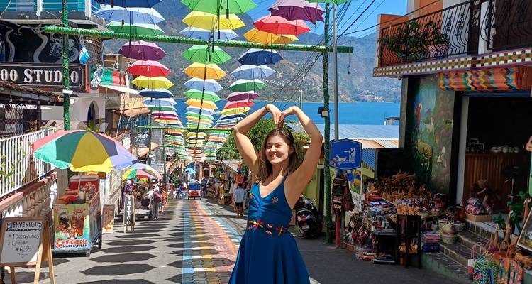 Mujer feliz posando bajo sombrillas coloridas en una calle.