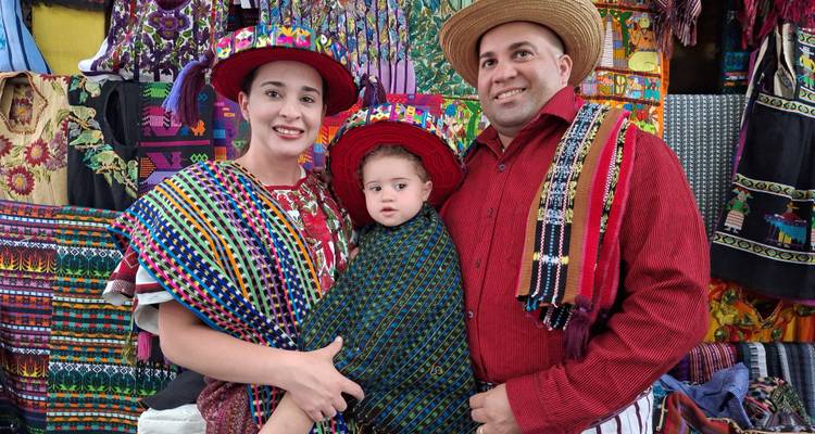 Familia vistiendo ropa tradicional posando frente a textiles coloridos.