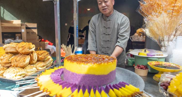 Verkoper die kleurrijke desserts en snacks toont.