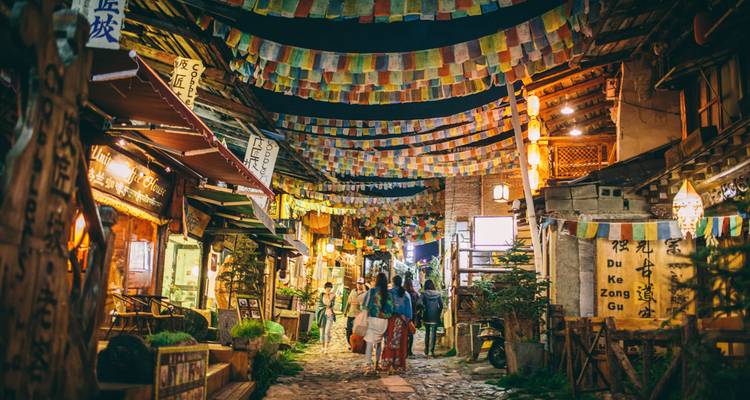 Nachtaanzicht van een kleurrijke straat met Tibetaanse gebedsvlaggen.