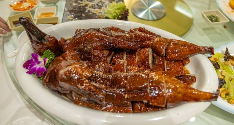 Hele gebraden eend geserveerd met decoratieve garnituur.