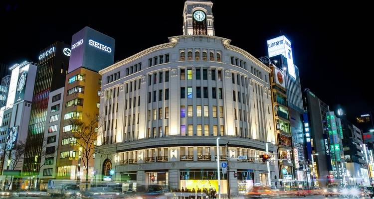 Un grand bâtiment avec une tour d'horloge dans un quartier animé de la ville la nuit.