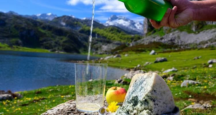 Sirviendo sidra tradicional con un telón de fondo montañoso.