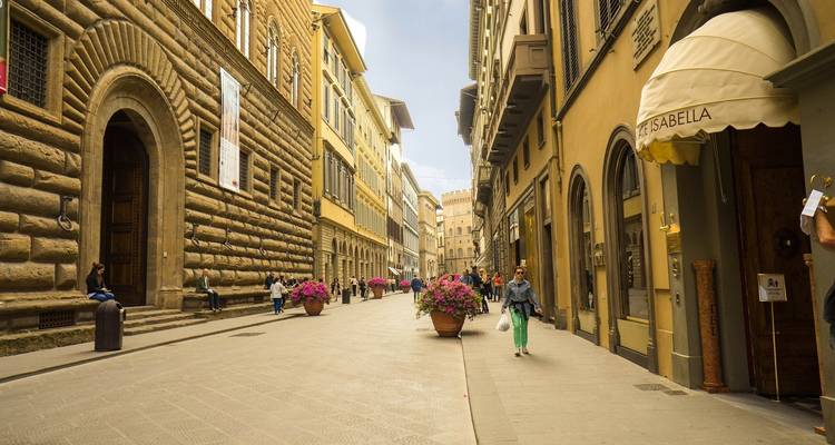Straßenansicht in Florenz mit historischen Gebäuden und Blumen.