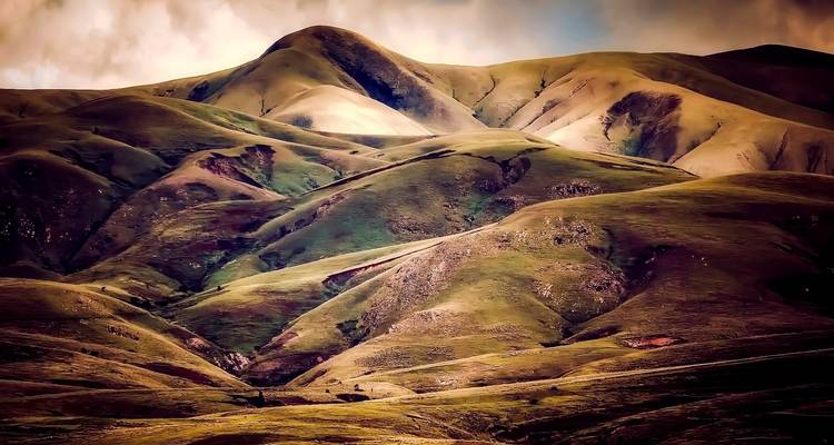 Paisaje montañoso erosionado con diversos tonos de vegetación.