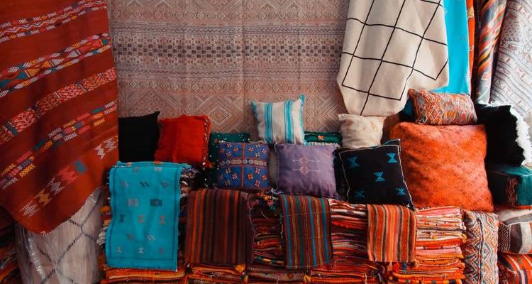 Textiles coloridos y cojines exhibidos en un puesto del mercado.