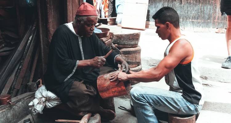 Dos hombres trabajando en artesanía de metal de manera tradicional.