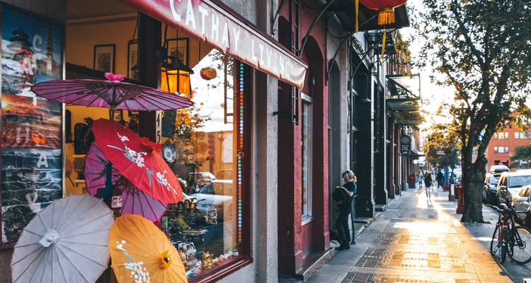 Charming shopfront with colorful parasols in a narrow Chinatown street lit by late-day sun.
