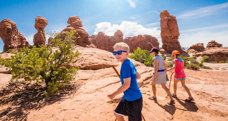 Familie met kinderen die wandelen tussen grappige zandstenen hoodoos en spitsen onder de felle zon.