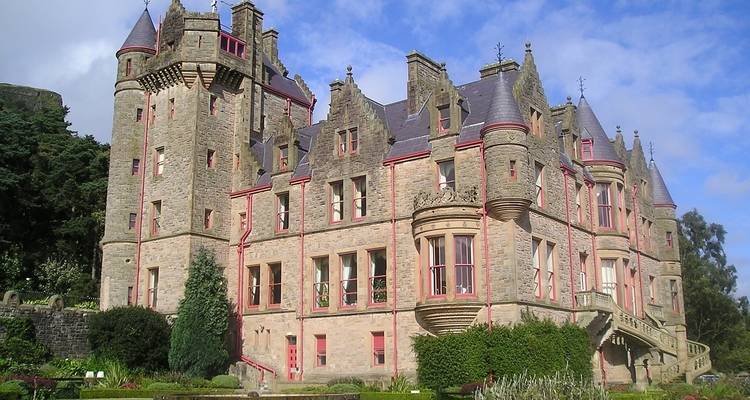 Château avec des jardins luxuriants dans un cadre historique.