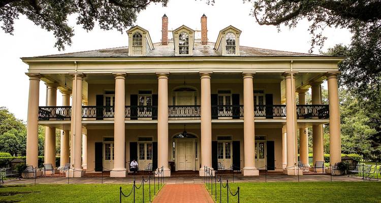 Una casa de plantación histórica con columnas y una entrada grandiosa, probablemente en Nueva Orleans.