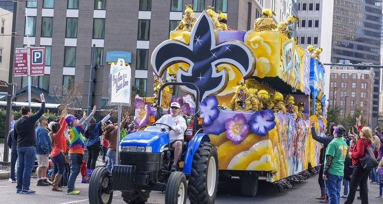 Una carroza colorida en un desfile con gente saludando.