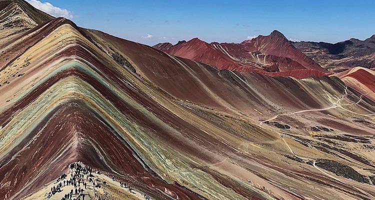 Les pentes rayées spectaculaires de la montagne arc-en-ciel avec des randonneurs minuscules contre les crêtes colorées.
