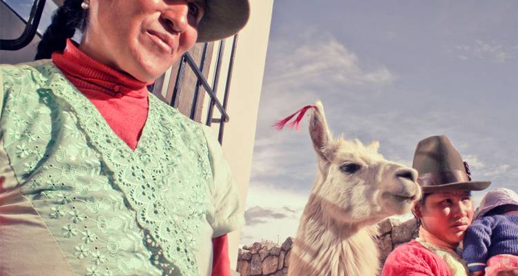 Des habitants portant des chapeaux traditionnels se tiennent aux côtés d'un lama blanc sous un ciel andin éclatant.