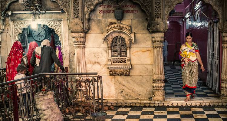 Interior vibrante de un templo hindú con mujeres en saris coloridos realizando rituales.
