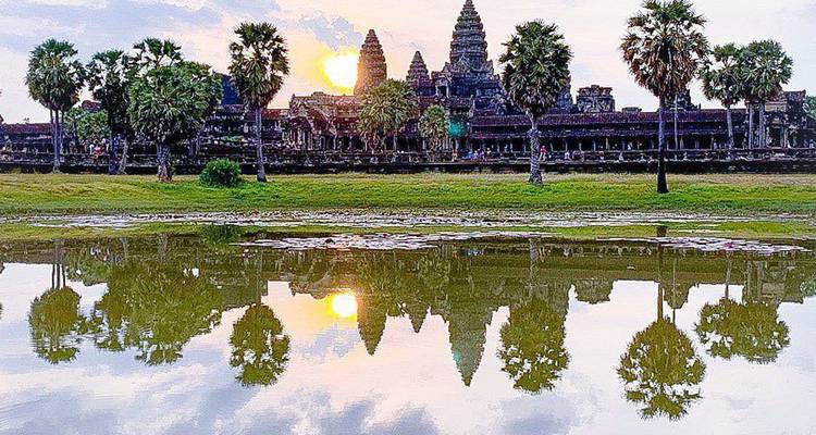Reflet de coucher de soleil à haut contraste d'Angkor Wat et des palmiers environnants dans les douves.