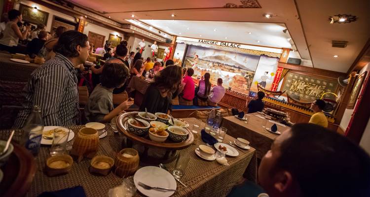 Espectáculo tradicional tailandés con cena donde los huéspedes se sientan en mesas bajas viendo a los artistas en el escenario