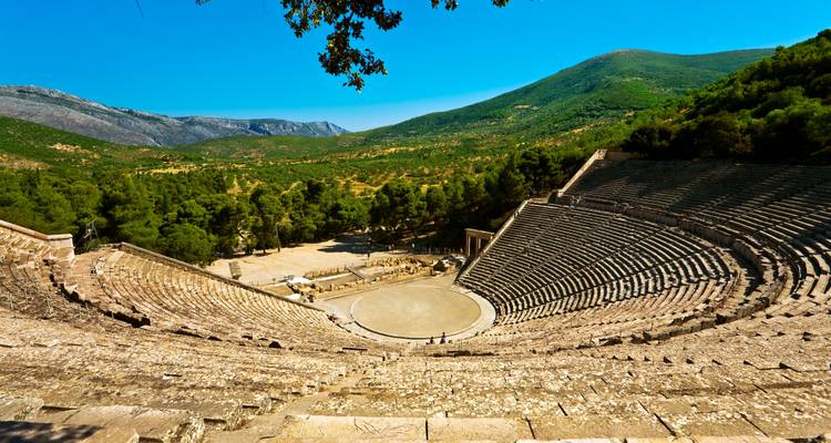 Grand amphithéâtre antique situé dans un paysage de montagne.
