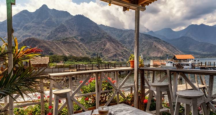 Lakeside café-terras met uitzicht op dramatische vulkaanbergen en water bij Meer Atitlán