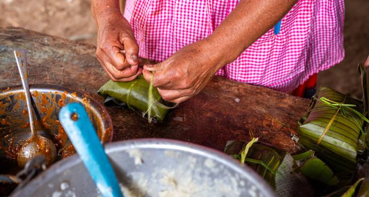 Hands wrap tamales in banana leaves during traditional Guatemalan cooking