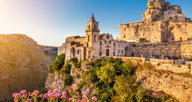 Ville historique de Matera avec des bâtiments sur une falaise au coucher du soleil.