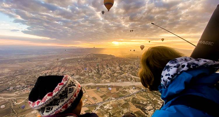 Vista desde un globo aerostático al amanecer con muchos otros globos flotando sobre los valles de Capadocia.